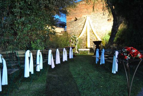 Filera de cadires amb xals blancs i blaus al capvespre, amb l'arc de teles al fons
