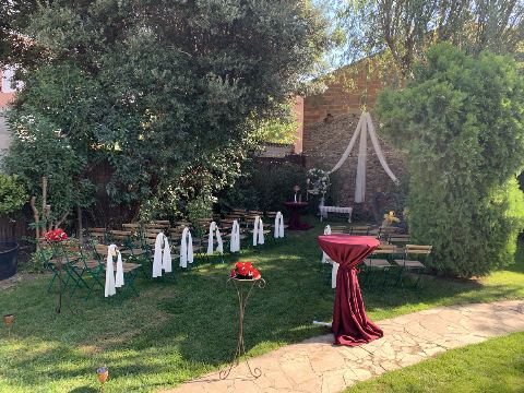 Jardí preparat per a la cerimònia, amb taula alta granat i camí de pedra