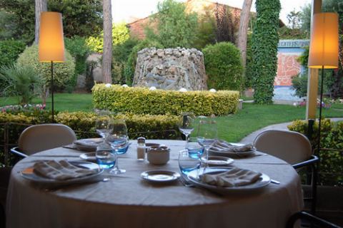 Taula parada amb làmpades de peu, el jardí i la font al fons