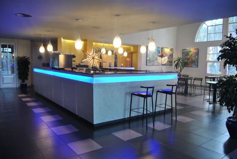 Bar del saló amb barra il·luminada en blau i tamborets alts