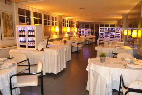 Sala amb taules parades i vitrines de vi il·luminades al fons