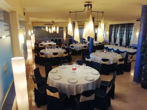 Sala àmplia amb cortines fosques, taules rodones i una columna blava